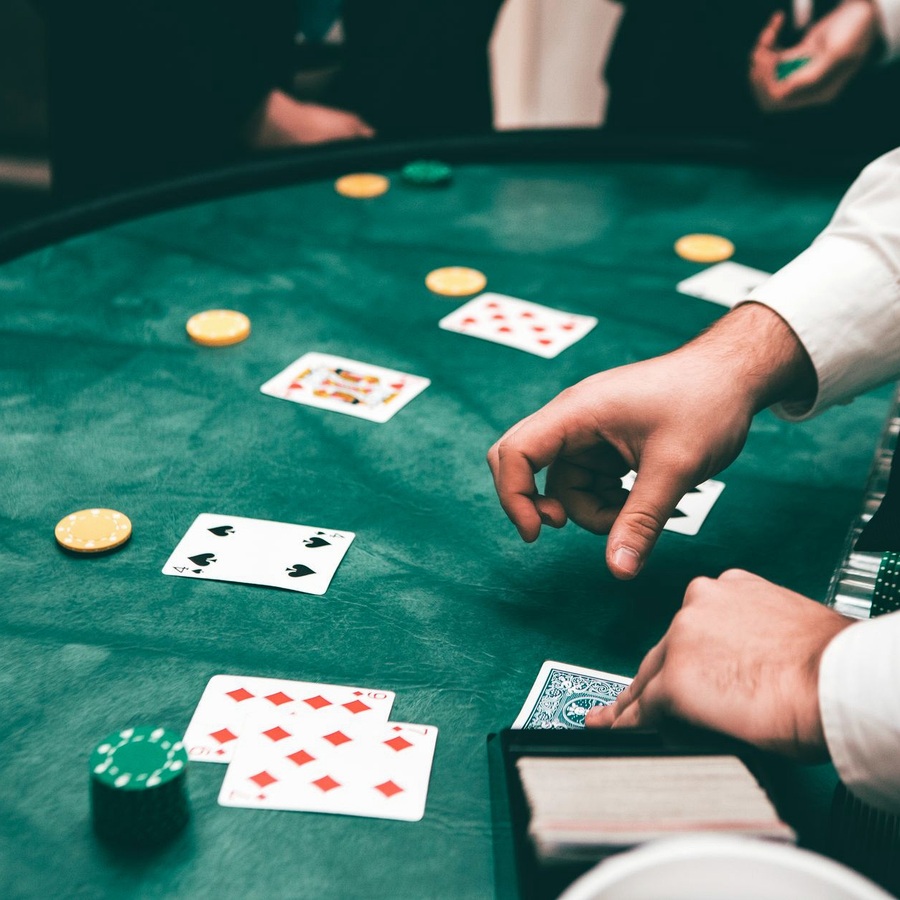 Dealer-host hands dealing cards across a felt table, guests out of frame