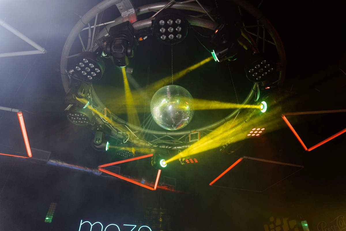 Dancefloor lit by coloured beams with a mirror ball overhead