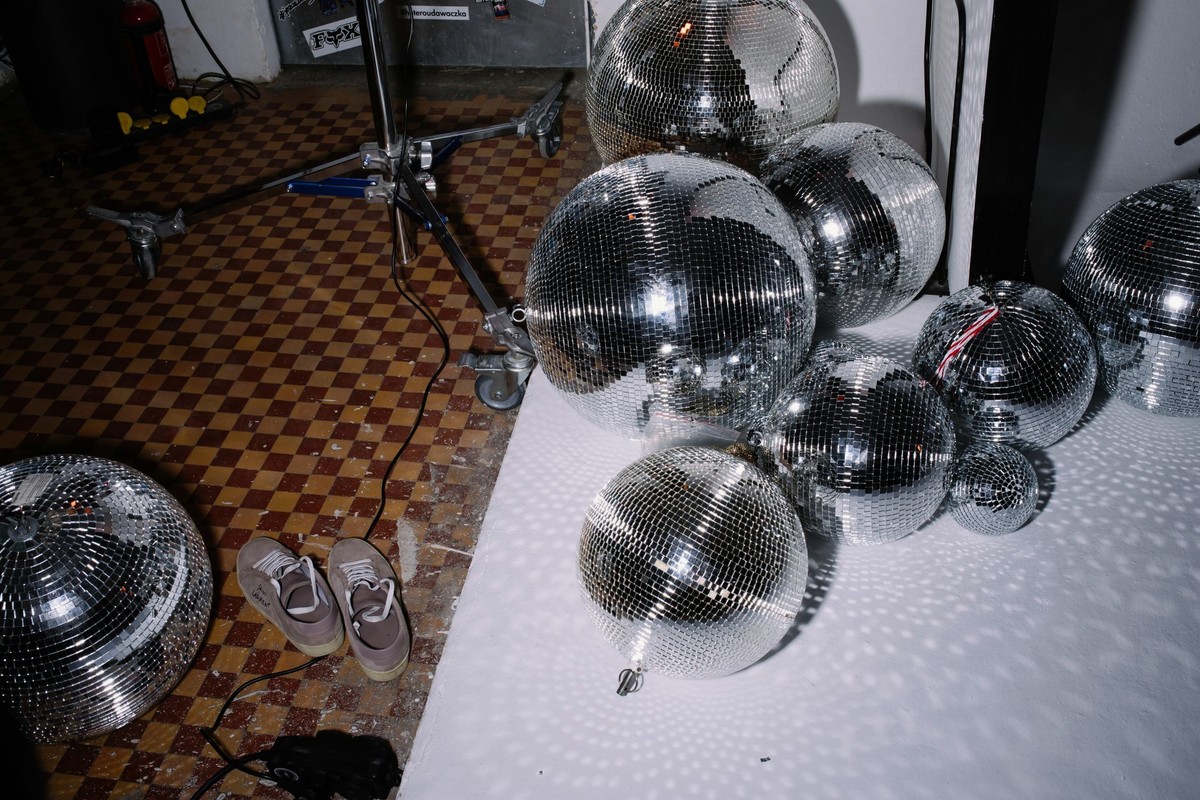 Mirror ball above a lit dancefloor with coloured light pools on the surface